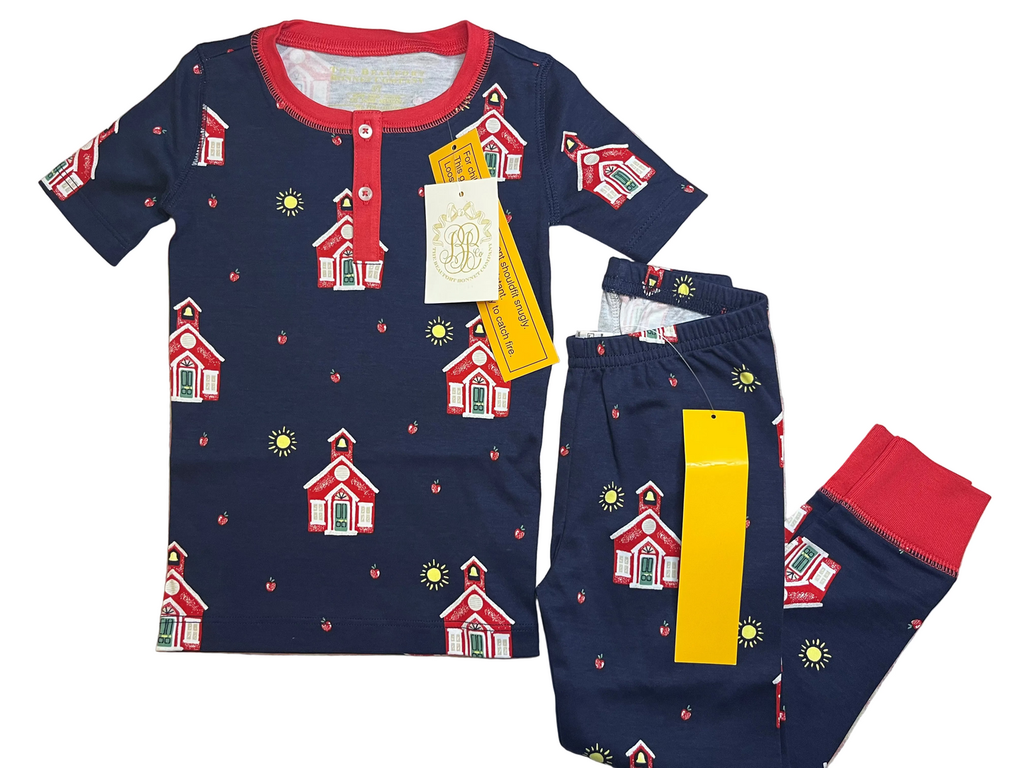Navy children's pajama set with red schoolhouse, sun, and apple print, short sleeves and tags attached.