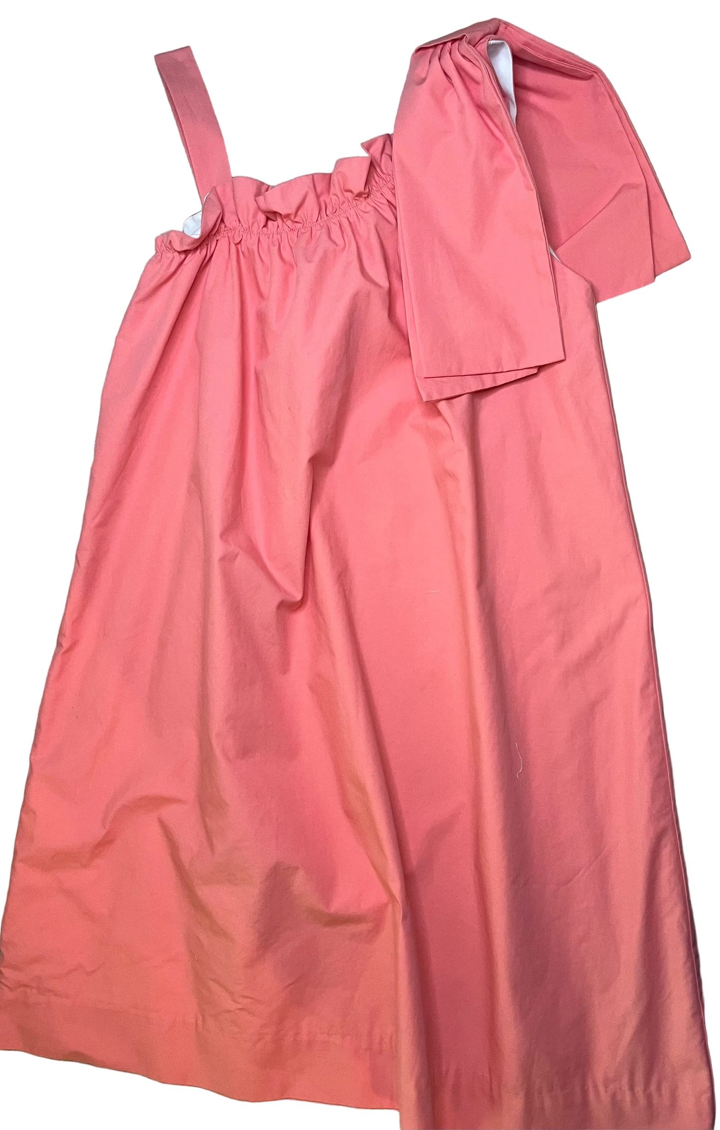 Coral pink girls sundress with ruffle neckline and single strap, displayed on patterned rug