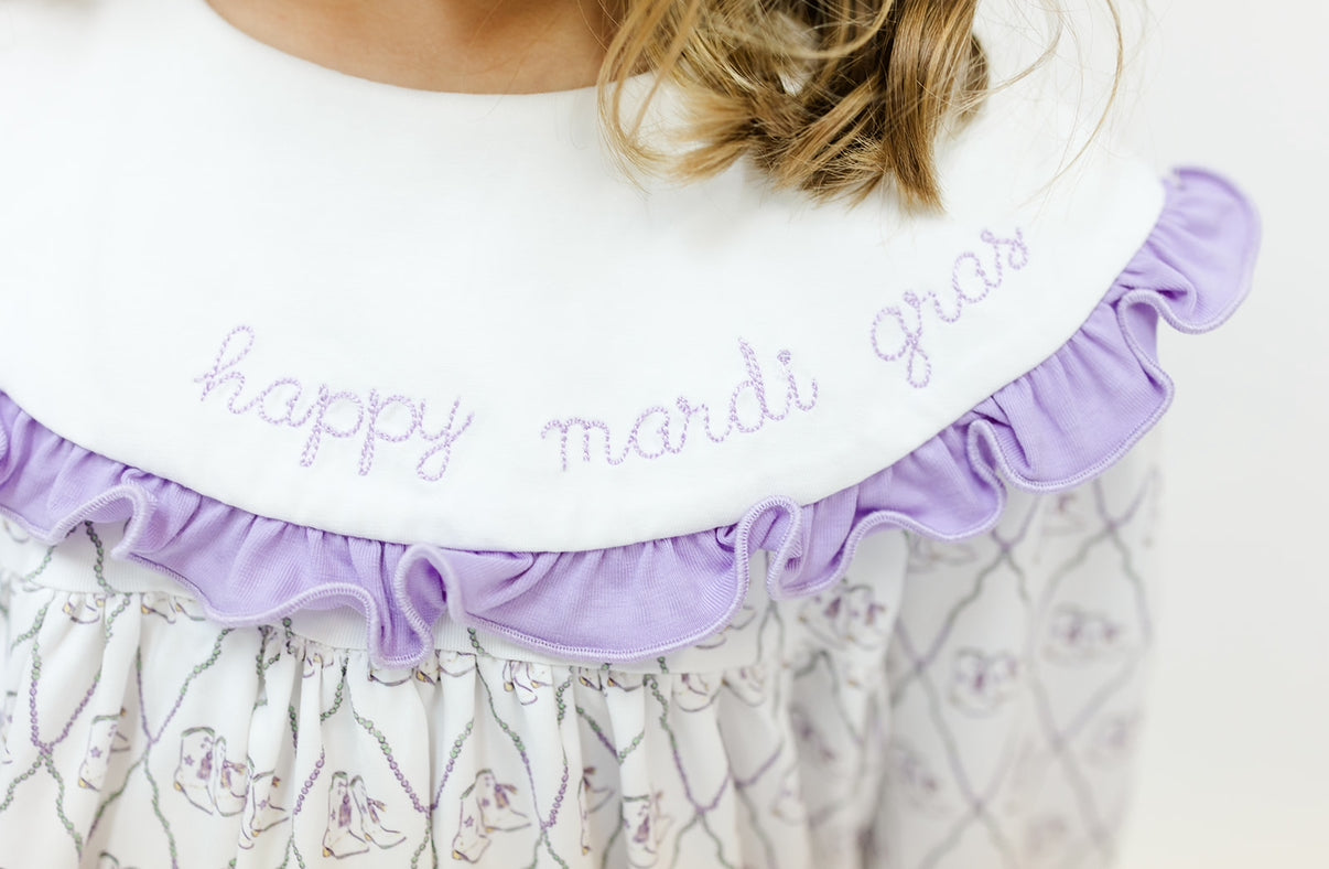 Girl wearing classic children's Mardi Gras dress with lavender ruffle and embroidered collar