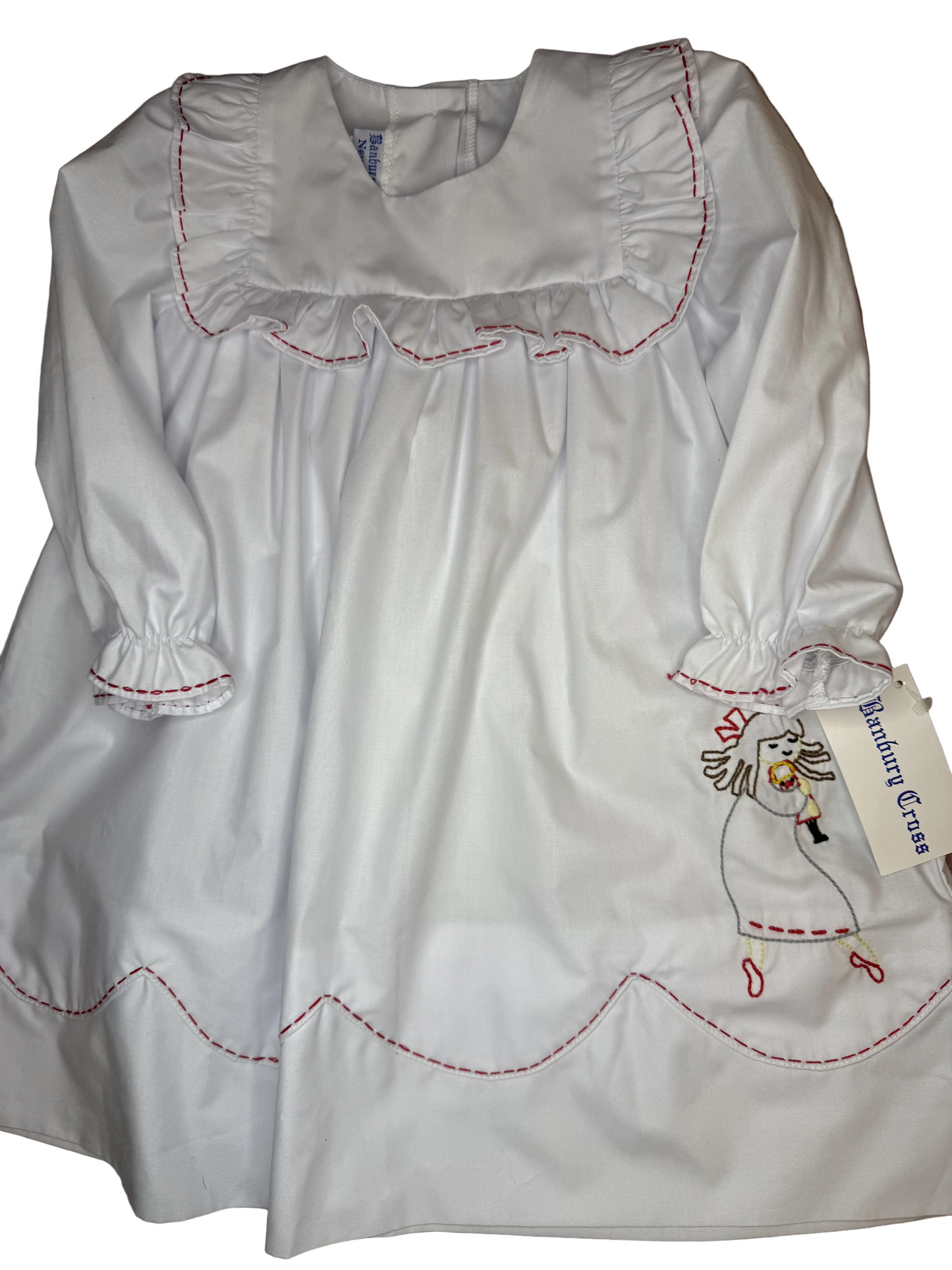 White long sleeve girls dress with red stitching, ruffle collar, and nursery rhyme embroidery.