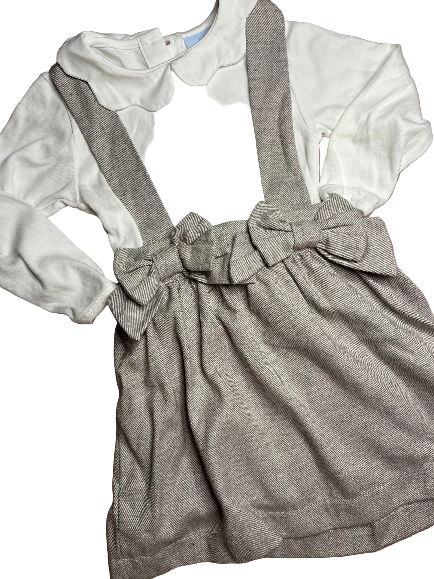 Classic girls outfit with white scalloped blouse and grey suspender skirt with bows