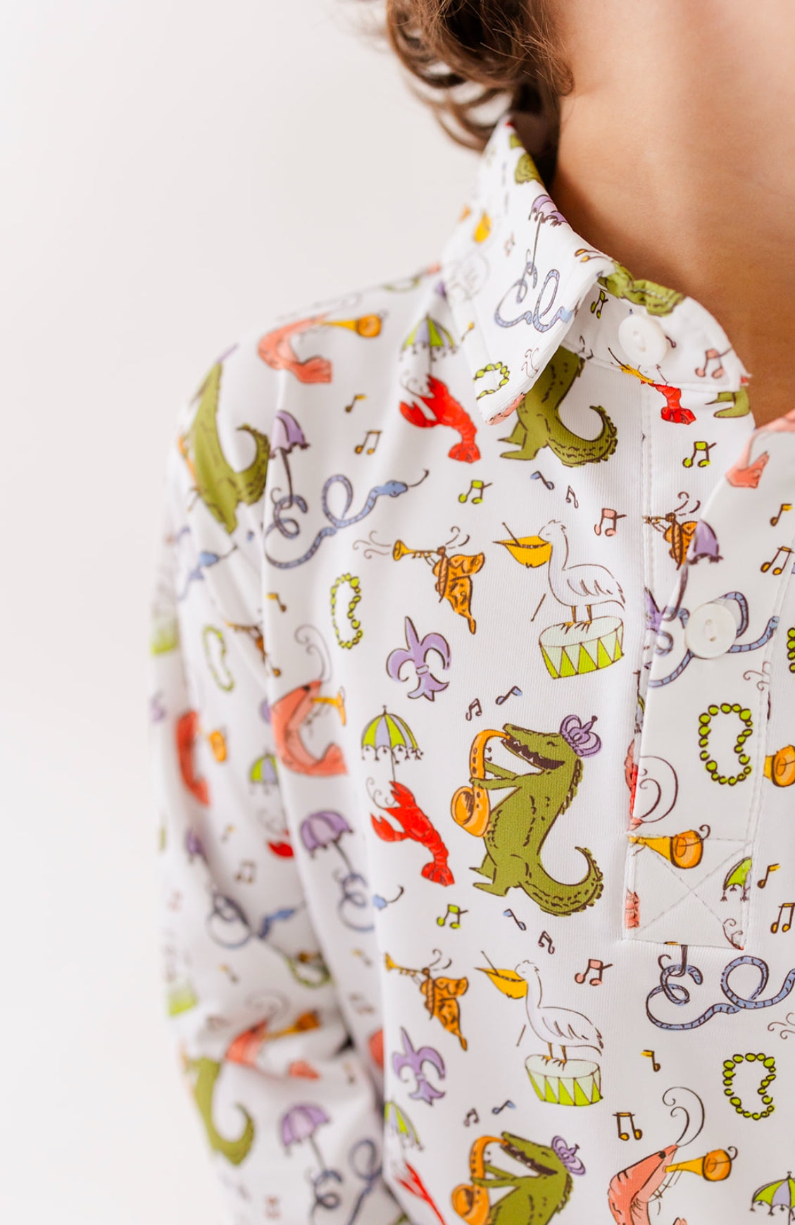 Boy wearing white collared shirt with colorful animal and music print, kids clothing fashion