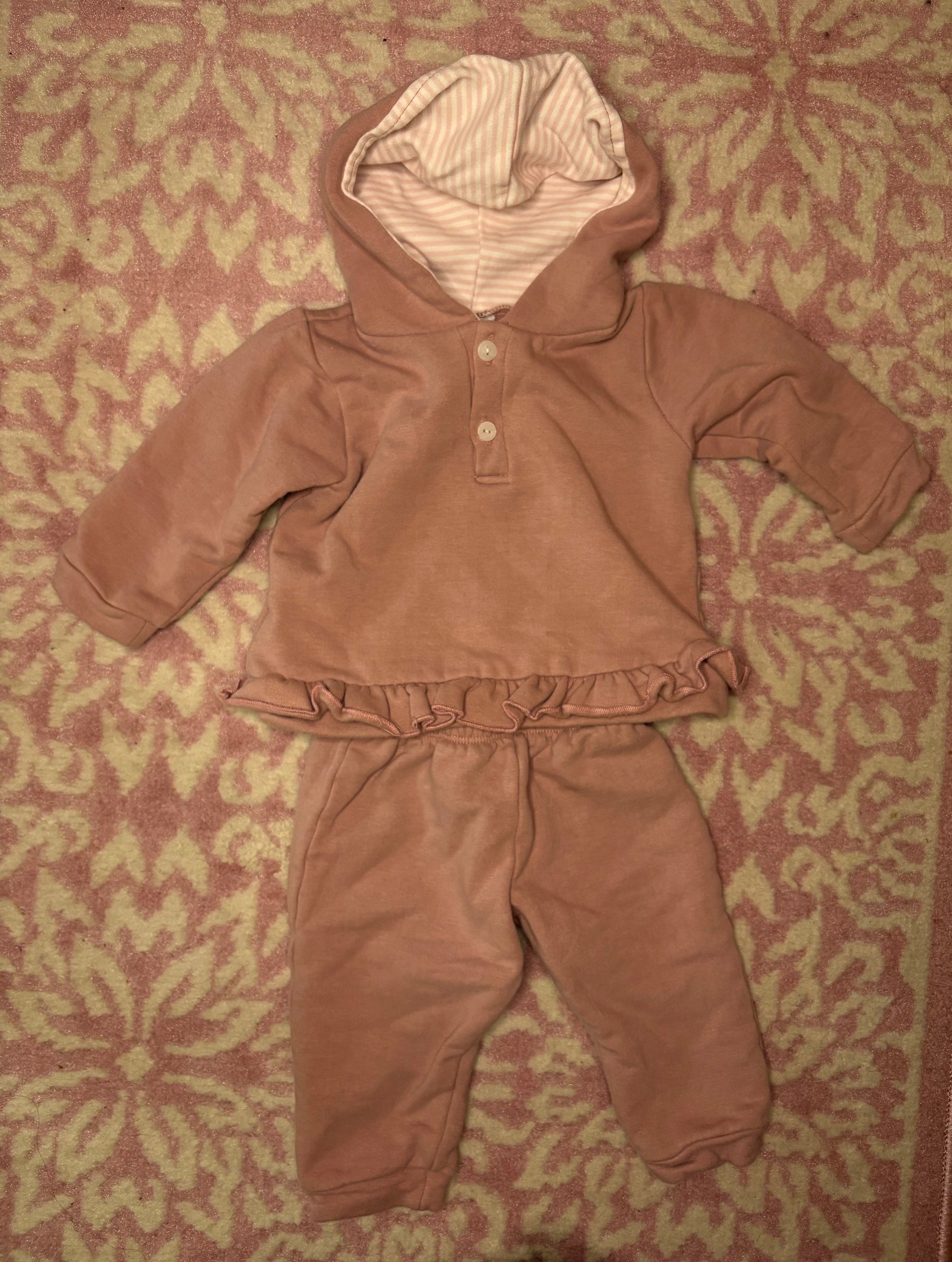 Pink toddler hooded ruffle lounge set with striped lining on patterned carpet